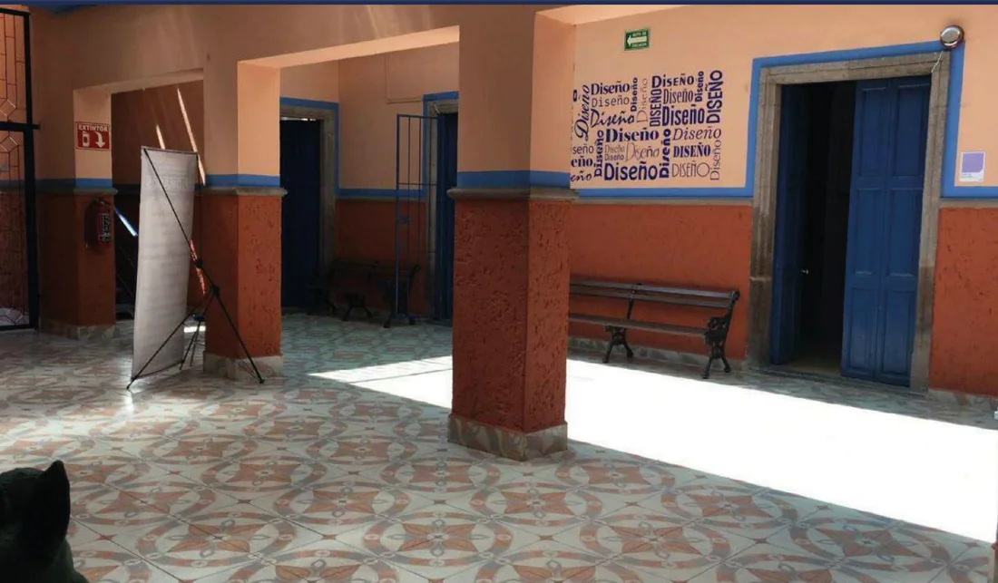 Pasillo con columnas, puertas azules y bancas de madera