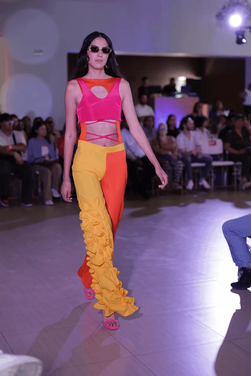 Look color-block en rosa, naranja y amarillo, con pantalón acampanado y aplicaciones de pétalos.