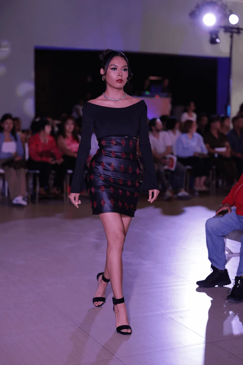 Top negro de hombros descubiertos con mangas campana y falda con apliques romboidales rojos.