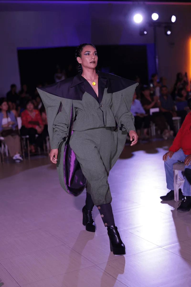 Sastre gris verdoso de hombros exagerados con capa y pantalón globo.